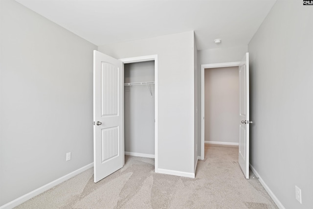 unfurnished bedroom with light colored carpet and baseboards