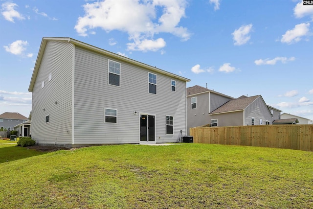 back of property with a yard, fence, and central AC