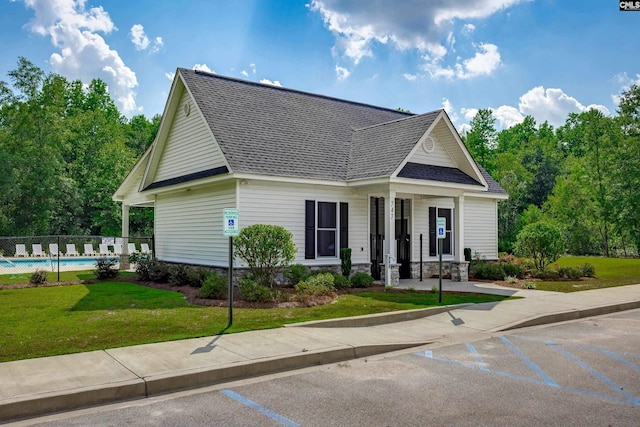 view of front of property with a front yard, a fenced in pool, fence, and a shingled roof