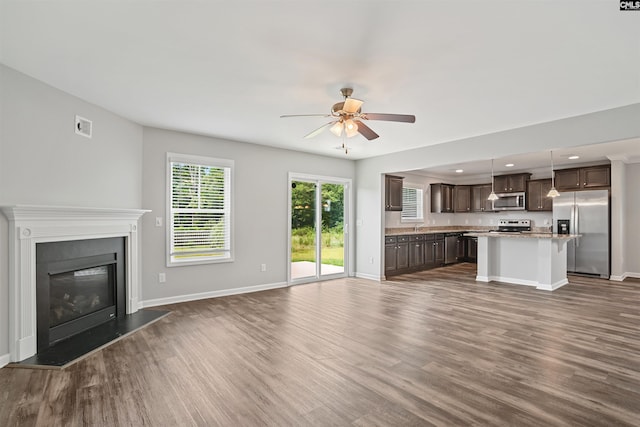 unfurnished living room featuring dark wood-style floors, baseboards, and ceiling fan