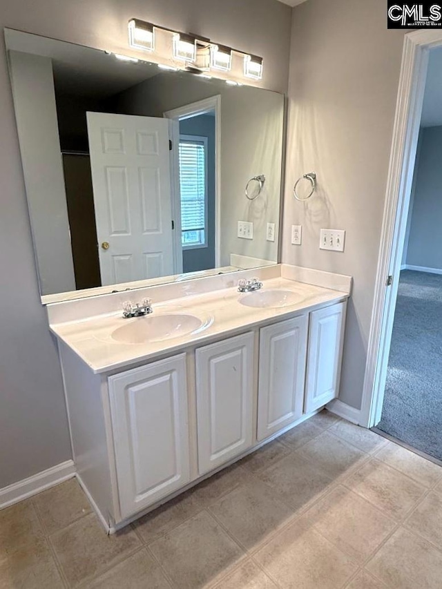 full bathroom with double vanity, baseboards, and a sink