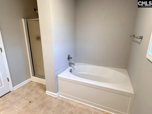 bathroom featuring a bath, tile patterned floors, a stall shower, and baseboards