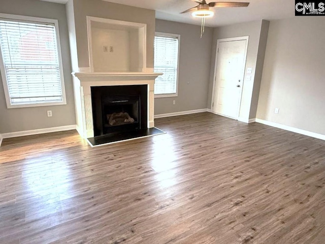 unfurnished living room featuring dark wood-style floors, a fireplace, baseboards, and ceiling fan