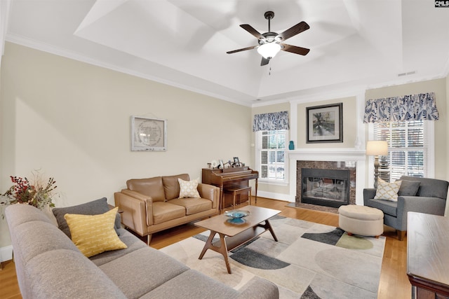 living room with a ceiling fan, a tray ceiling, plenty of natural light, and wood finished floors