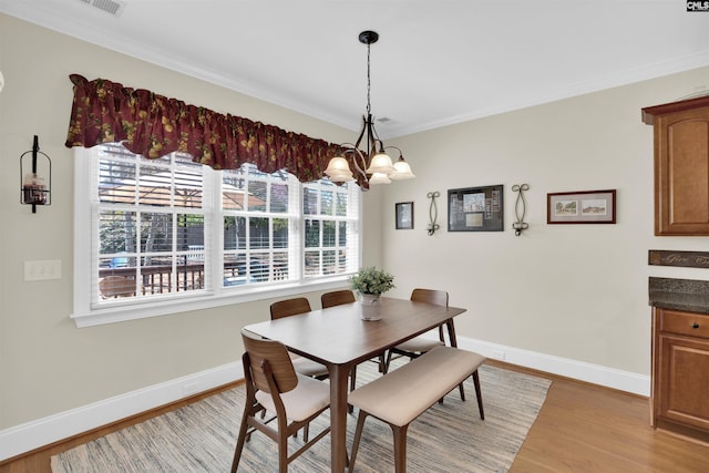 dining room featuring a notable chandelier, baseboards, crown molding, and light wood-style floors