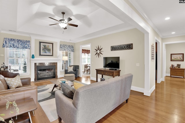 living area with light wood finished floors, a healthy amount of sunlight, a ceiling fan, and a premium fireplace