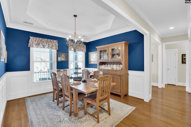 dining room featuring a raised ceiling, a notable chandelier, visible vents, and light wood-type flooring