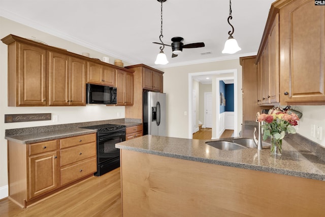 kitchen with light wood-type flooring, ornamental molding, a peninsula, black appliances, and a sink