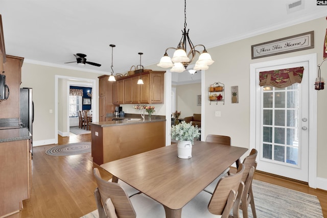 dining room featuring visible vents, crown molding, baseboards, ceiling fan with notable chandelier, and wood finished floors