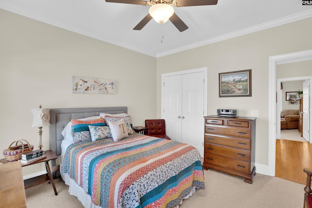 bedroom featuring baseboards, ceiling fan, ornamental molding, a closet, and light carpet