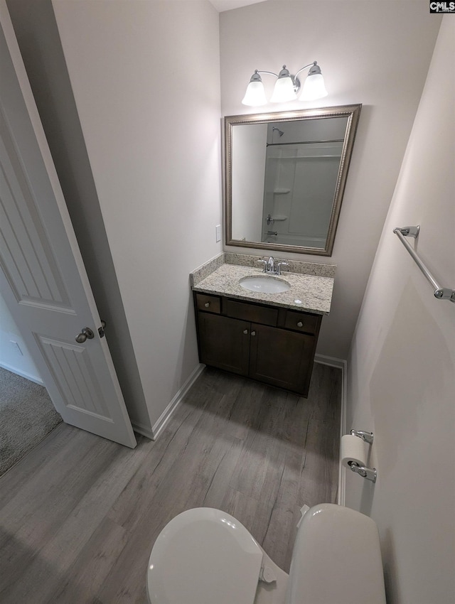 bathroom featuring toilet, vanity, baseboards, and wood finished floors