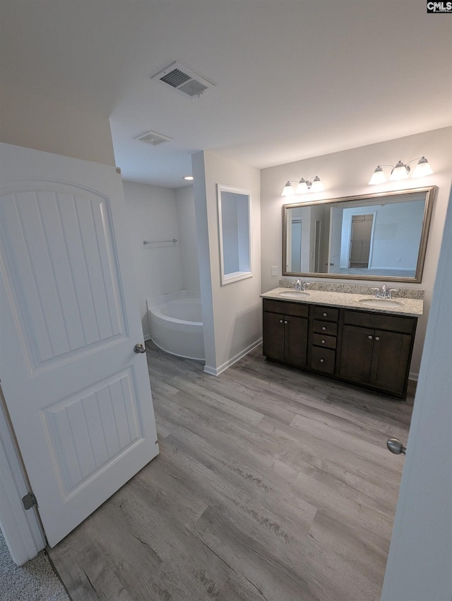 bathroom featuring double vanity, a bath, visible vents, and a sink