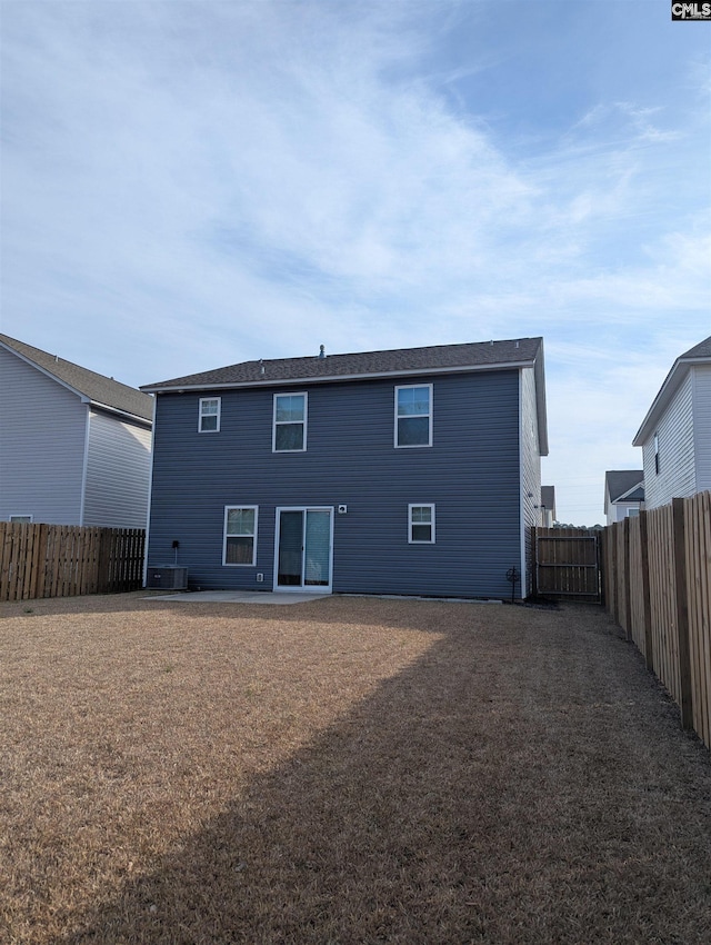 rear view of property featuring a yard and a fenced backyard