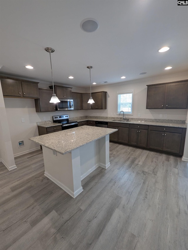 kitchen featuring a sink, a kitchen island, appliances with stainless steel finishes, light wood finished floors, and dark brown cabinets