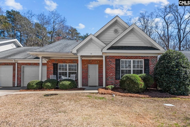 view of front of home featuring driveway, roof with shingles, an attached garage, a front yard, and brick siding