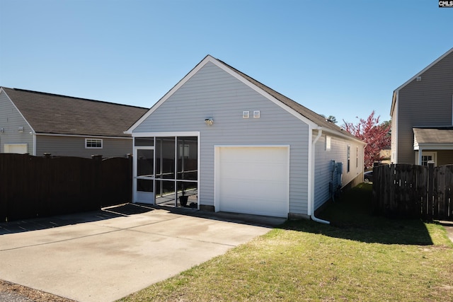 back of property featuring fence, a garage, a sunroom, and a lawn