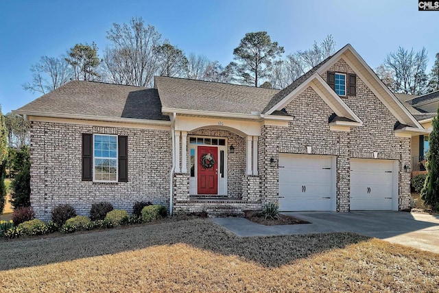 view of front of property with an attached garage, roof with shingles, and driveway