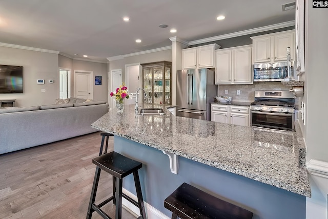 kitchen with visible vents, light stone countertops, white cabinets, stainless steel appliances, and a sink