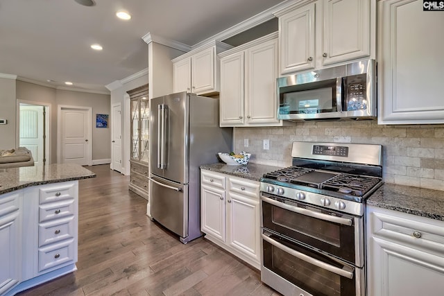 kitchen featuring dark wood-style floors, dark stone counters, ornamental molding, appliances with stainless steel finishes, and white cabinetry