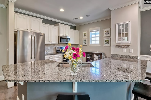 kitchen featuring light stone countertops, a breakfast bar, decorative backsplash, appliances with stainless steel finishes, and crown molding