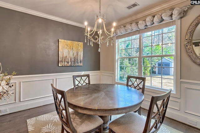 dining space with wood finished floors, visible vents, ornamental molding, wainscoting, and a chandelier