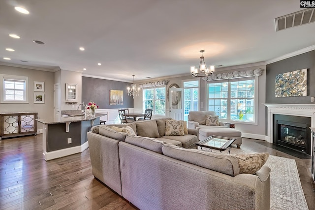 living area with a chandelier, visible vents, dark wood-style floors, and ornamental molding