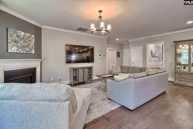 living room featuring wood finished floors, baseboards, visible vents, ornamental molding, and a notable chandelier