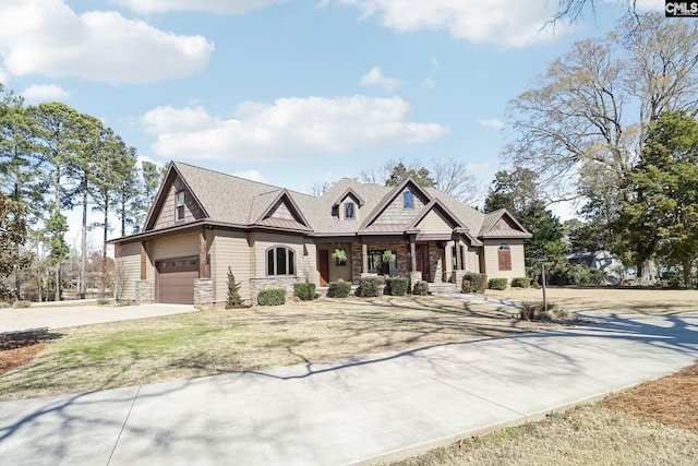 view of front of home featuring stone siding, a front yard, and driveway