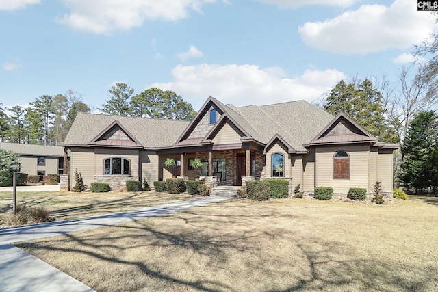 craftsman house with a standing seam roof, a front yard, stone siding, and metal roof