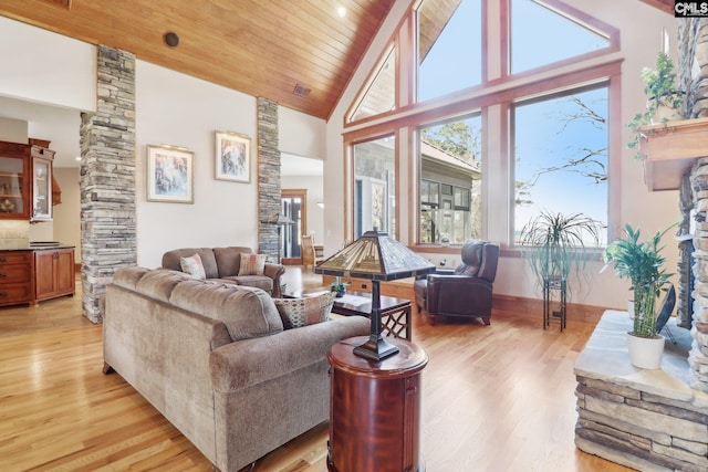 living area featuring ornate columns, high vaulted ceiling, a fireplace, wooden ceiling, and light wood-type flooring