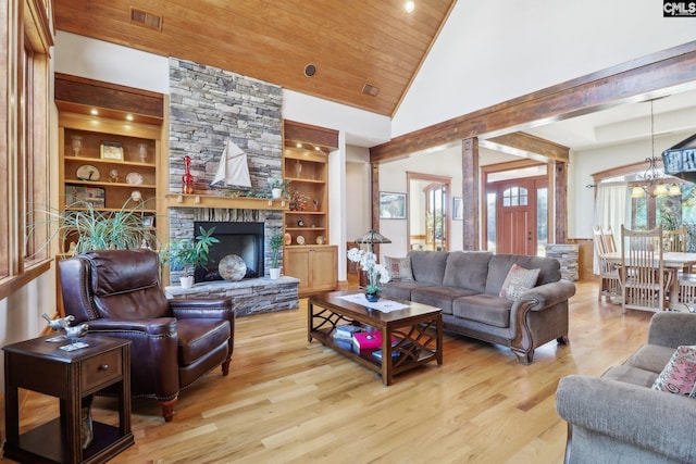 living room with built in features, wood finished floors, high vaulted ceiling, a stone fireplace, and wooden ceiling