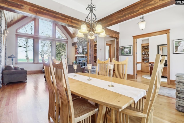 dining area featuring built in features, baseboards, beamed ceiling, light wood-type flooring, and a chandelier