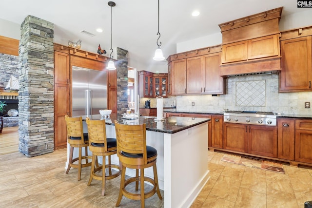 kitchen with dark stone countertops, a center island, appliances with stainless steel finishes, decorative backsplash, and hanging light fixtures