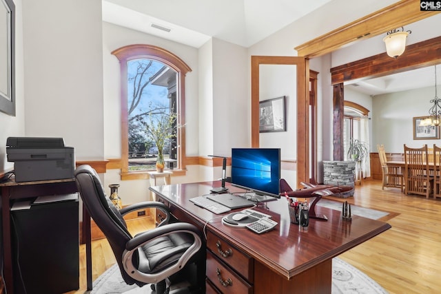 office with light wood finished floors, visible vents, and an inviting chandelier