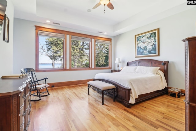 bedroom with visible vents, a raised ceiling, recessed lighting, light wood finished floors, and baseboards