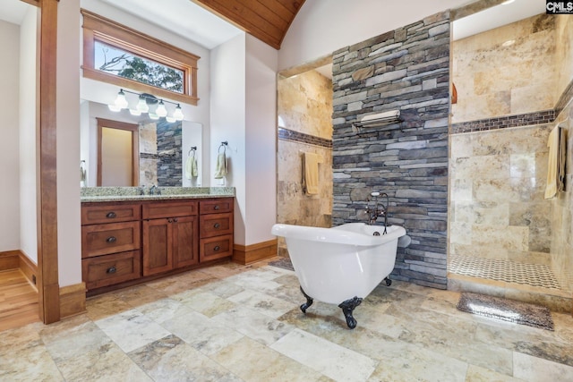 bathroom featuring vanity, baseboards, tiled shower, lofted ceiling, and a freestanding bath