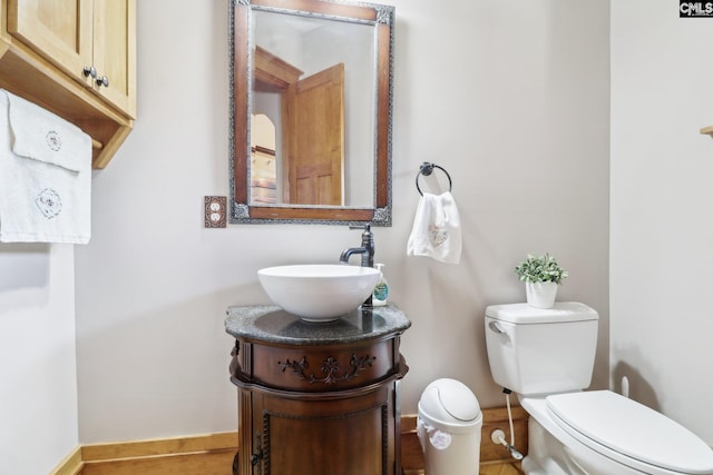 bathroom featuring toilet, vanity, and baseboards