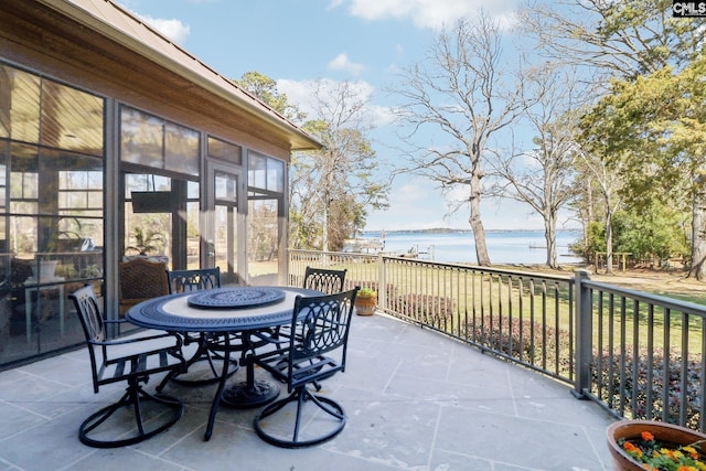 view of patio / terrace with outdoor dining area, a sunroom, and a water view