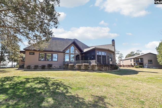 rear view of property with crawl space, a yard, a chimney, and a sunroom