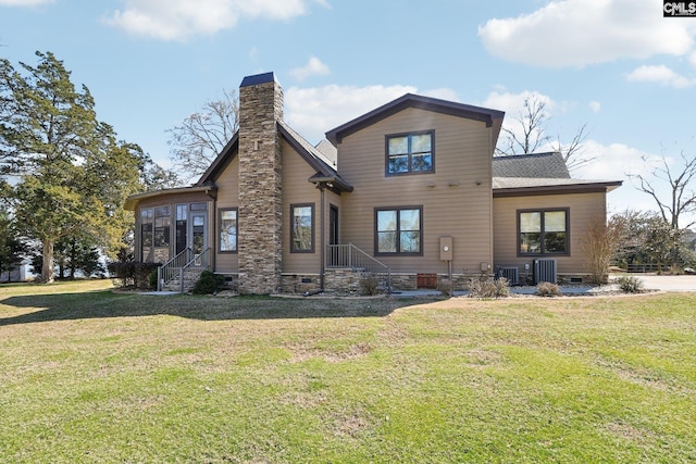 rear view of house featuring a lawn, a chimney, a sunroom, and crawl space