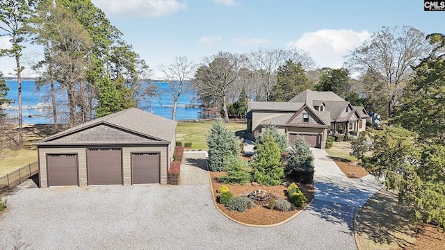 view of front of property with fence, a water view, a garage, stone siding, and driveway