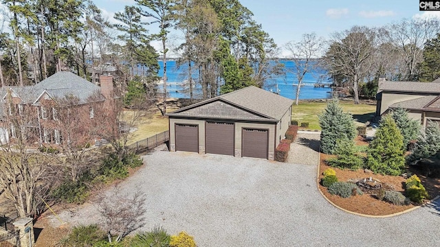 garage featuring fence, a water view, and driveway