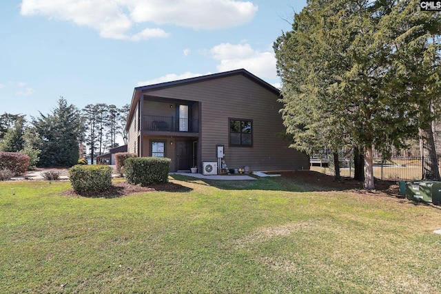 rear view of house featuring a lawn, a balcony, and fence