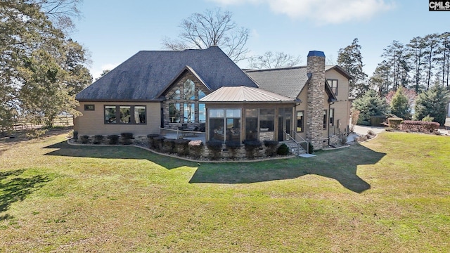 rear view of house featuring a lawn, a sunroom, and a chimney