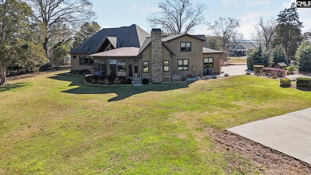 rear view of property with metal roof, a lawn, and a chimney