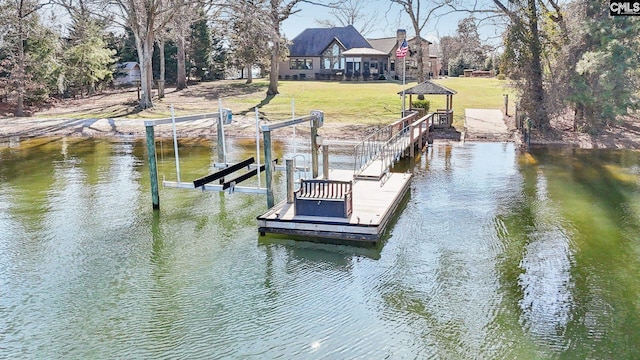 dock area featuring boat lift, a yard, and a water view