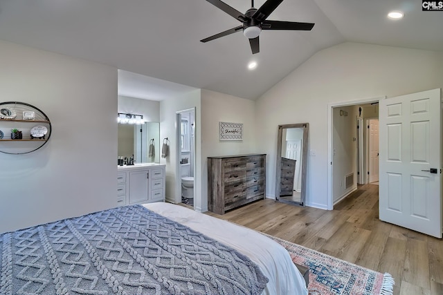 bedroom featuring visible vents, light wood-style flooring, a sink, vaulted ceiling, and ensuite bathroom