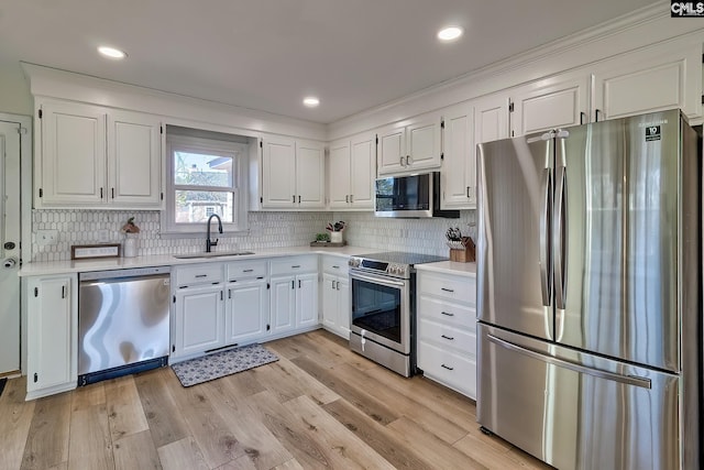 kitchen featuring light countertops, light wood-type flooring, appliances with stainless steel finishes, and a sink