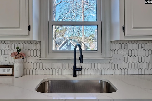 kitchen featuring white cabinetry, decorative backsplash, and a sink