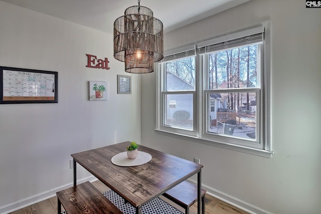 dining room featuring light wood-style flooring, baseboards, and a chandelier